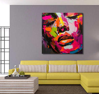 Françoise Nielly-signature - Dora by Night: A vibrant, abstract oil portrait of a woman's face, featuring bold brushstrokes, displayed above a modern yellow sofa.