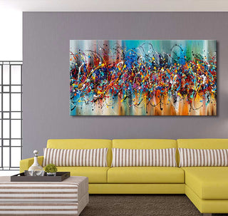 Jackson Pollock signature 'Colorful Days' canvas art above a yellow L-shaped sofa with striped cushions; abstract splatter style in a modern living room setting.
