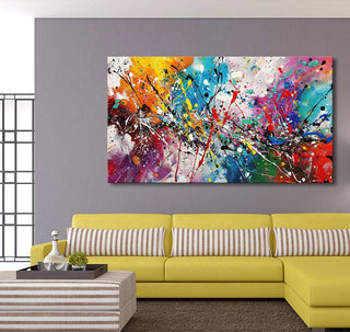 Modern living room featuring Jackson Pollock signature - The Bright Side abstract canvas in vibrant colors, above a yellow L-shaped sofa and striped ottoman.