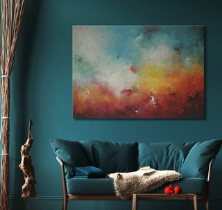 Abstract canvas painting 'Early Evening Sky' in blues and oranges above a teal loveseat, complemented by natural wood elements, creating a modern, nature-inspired nook.