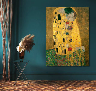 Gustav Klimt – De Kus (60x90cm) hand-painted oil on canvas, mounted on a teal wall, next to a black side table with a vase of dried grasses.