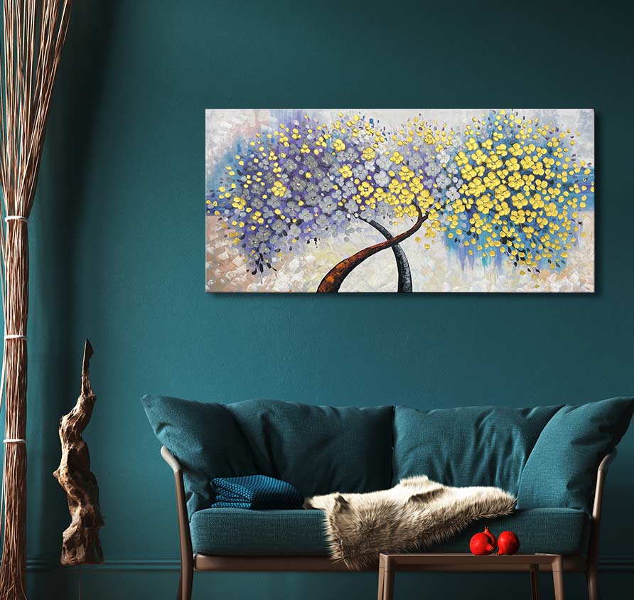 Twee bomen in bloei op het schilderij Tree Romance – Dikke olieverf op canvas, hangend boven een teal bank, met decoratieve takken en een houten salontafel.