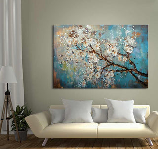 Pluimbloesem - Olieverf op canvas toont een bloeiende tak tegen een blauw-gouden achtergrond, passend bij moderne interieurs. Gecombineerd met een laag crèmekleurige bank.