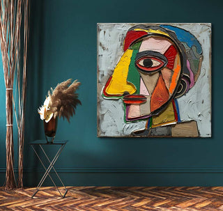 Cubist-style portrait Le Lapin Agile by Picasso, featuring vibrant colors, hangs on a teal wall above a sleek metal table with dried pampas grass.