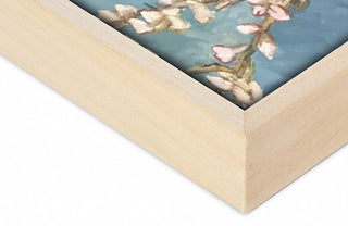 Naturel Baklijst: Close-up of mitered corner of a light-wood frame encasing a floral print with white and pink blossoms on a pale blue backdrop.