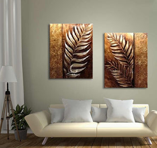 2-Luik Golden Leafs - Acrylverf op canvas met metalen varenmotief boven een crèmekleurige bank, naast een moderne vloerlamp en een groene plant.
