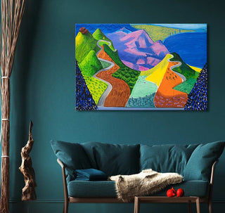 David Hockney's Driving through the Santa Monica Mountains oil painting, showcasing vibrant abstract hills, hangs above a teal sofa in a styled living-room scene.