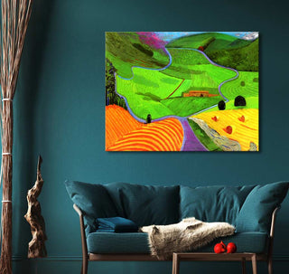 David Hockney's Garrowby Hill painting hangs above a teal sofa, showcasing a vibrant landscape with fields and a path. Perfect for modern art enthusiasts.