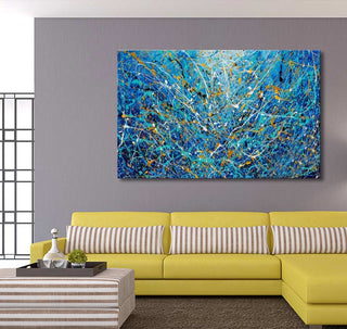 Abstract 'Aqua' painting in Pollock’s style, vibrant cobalt and gold drips, above a modern chartreuse sofa with striped accents in a contemporary living room setting.