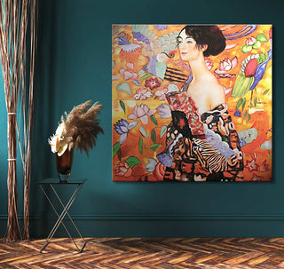 Gustav Klimt's Dame met Waaier portrait on canvas, hung on a teal wall. Nearby, a black side table with a pampas grass vase enhances the setting.